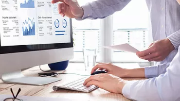 People analyzing financial data on a computer screen.