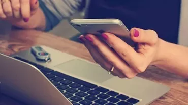Personne utilisant un smartphone près d'un ordinateur portable.