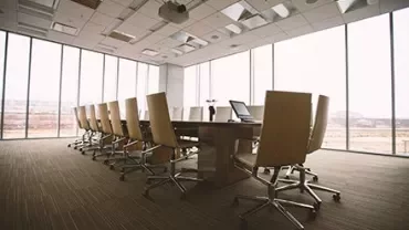 Empty conference room with a table and chairs, large windows.