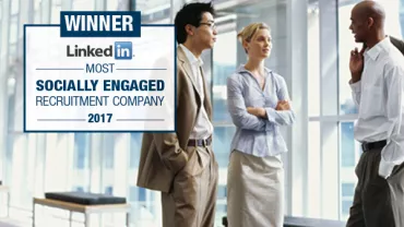 Three people talking in a modern office. LinkedIn award displayed.