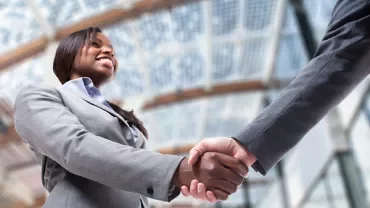 Two people shaking hands in a modern office setting.