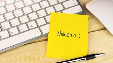 Sticky note with 'Welcome :)' next to a keyboard and pen.