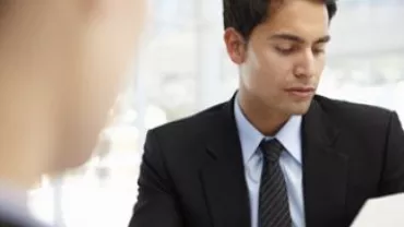 Person in a suit reading a document during a meeting.