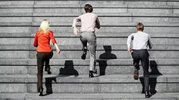 Three people in office attire ascending outdoor stairs.
