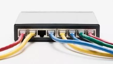 A black network switch with colorful Ethernet cables plugged in.