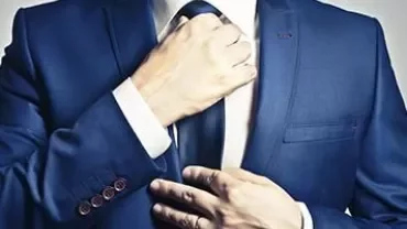 Person adjusting a blue suit and tie