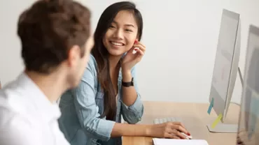 Deux personnes collaborant à un bureau avec des ordinateurs.