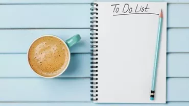 Coffee and a notebook with a 'To Do List' written, placed on a blue wooden table.