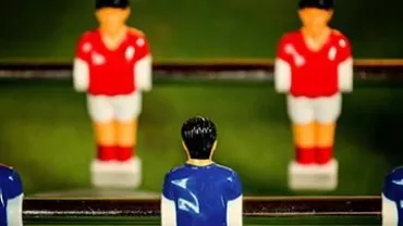 Table soccer figures with red and blue jerseys on rods.