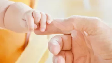 Un bébé tient doucement la main d'un adulte.
