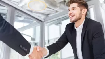 Personne d'affaires souriante serrant la main dans un bureau.