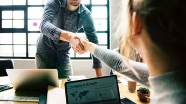 Two people shaking hands in an office setting.