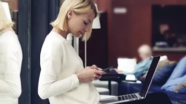 Person using a phone while sitting with a laptop.