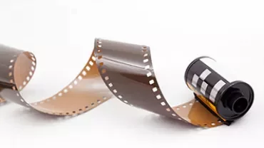 A roll of 35mm film partially unwound on a white background.