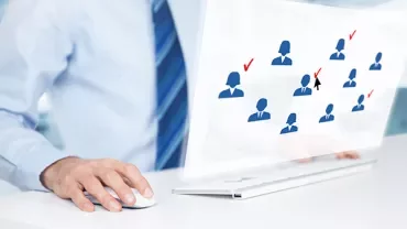 Personne utilisant un ordinateur avec un diagramme de silhouettes bleues et des coches à l'écran.