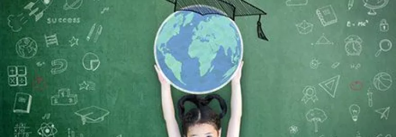 Child holding globe with a graduation cap drawn on chalkboard behind.