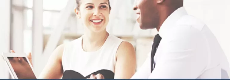 Two people having a discussion at a table with a tablet, LinkedIn award mentioned.