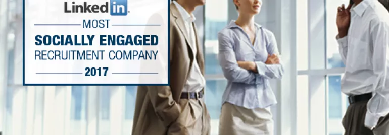 Three people talking in a modern office. LinkedIn award displayed.