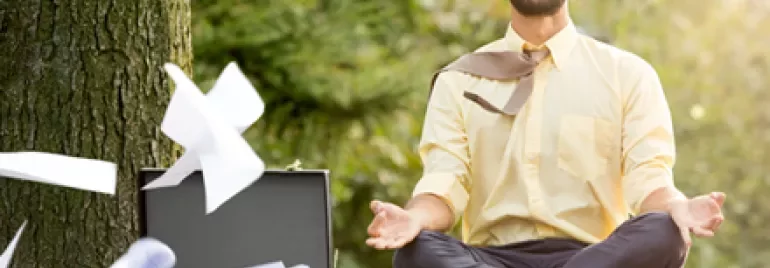 Person meditating outdoors with papers flying.