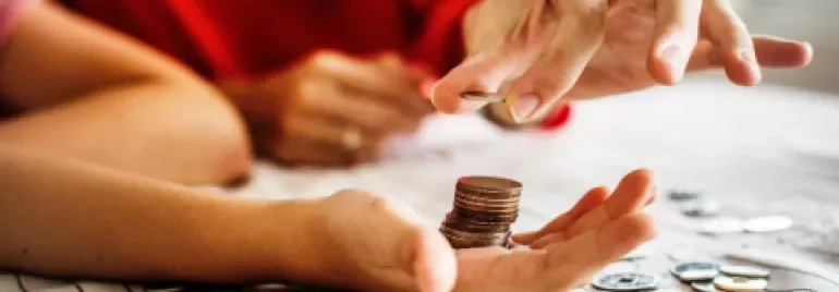 Hands counting coins on a table
