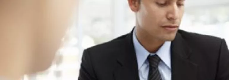 Person in a suit reading a document during a meeting.