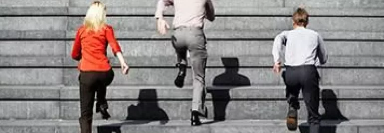 Three people in office attire ascending outdoor stairs.