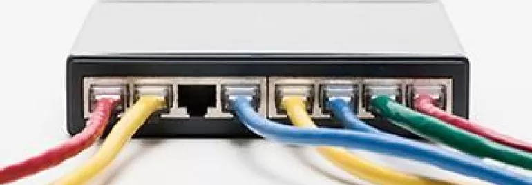 Un commutateur réseau noir avec des câbles Ethernet colorés branchés.