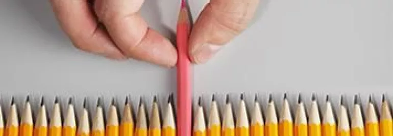A hand picking a red pencil among yellow pencils.