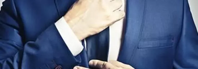 Person adjusting a blue suit and tie