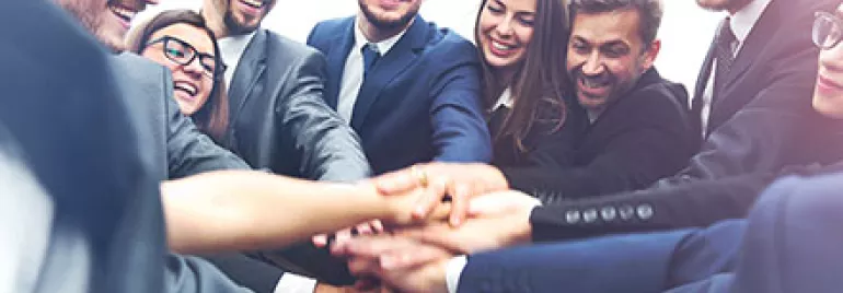 Équipe de professionnels se joignant les mains en cercle.