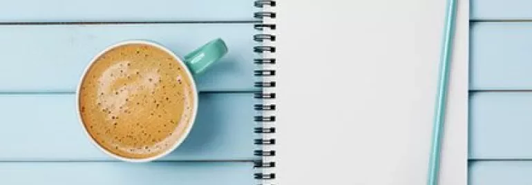 Notebook with 'To Do List' next to a cup of coffee on a blue table.