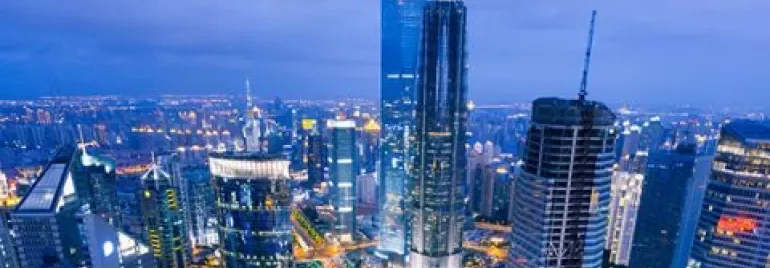 City skyline at night with tall illuminated buildings.