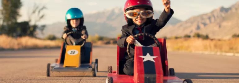 Enfants en kart avec des casques, l'un d'eux levant le bras de victoire.