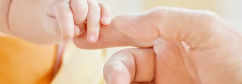 Un bébé tient doucement la main d'un adulte.