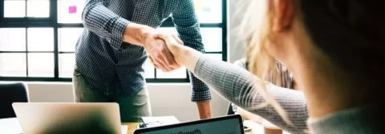 Deux personnes se serrant la main dans un bureau.