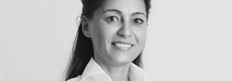 Person smiling in a white shirt, black and white photo.