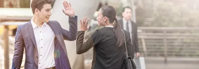 People exchanging high-fives in a modern outdoor setting.