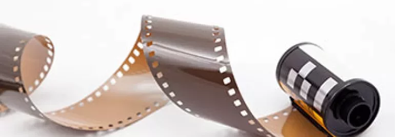 A roll of 35mm film partially unwound on a white background.
