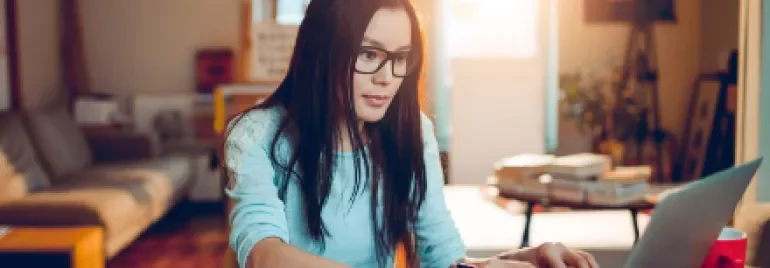 Person working on a laptop at a home office with books.