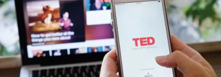 Personne utilisant un téléphone avec l'application TED ouverte, ordinateur portable en arrière-plan.