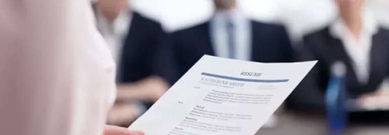 Une personne tient un CV devant des intervieweurs à une table.