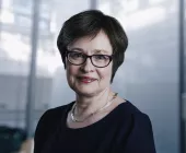 Person with short hair and glasses smiling indoors.