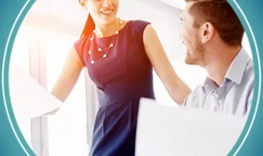 Two colleagues talking and smiling in a well-lit office.