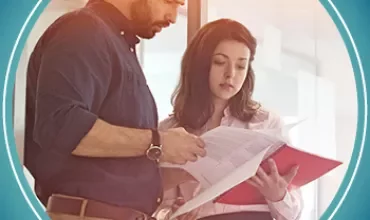 Two people review documents in an office setting.