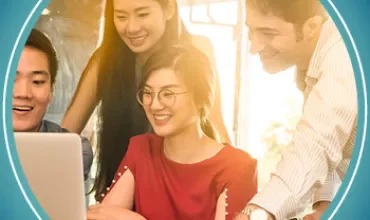 Group of people smiling and working together on a laptop.
