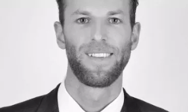 Person in a suit smiling in a black and white portrait.