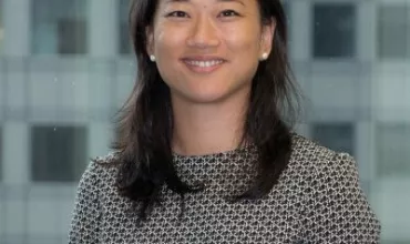 Person smiling in office attire with a city view background.