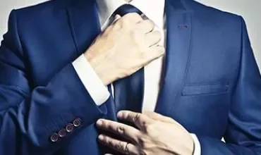 Personne ajustant un costume bleu et une cravate.