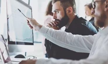 People collaborating at a computer in an office.