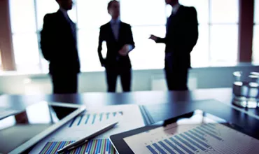 Business meeting with charts and tablets on a table.